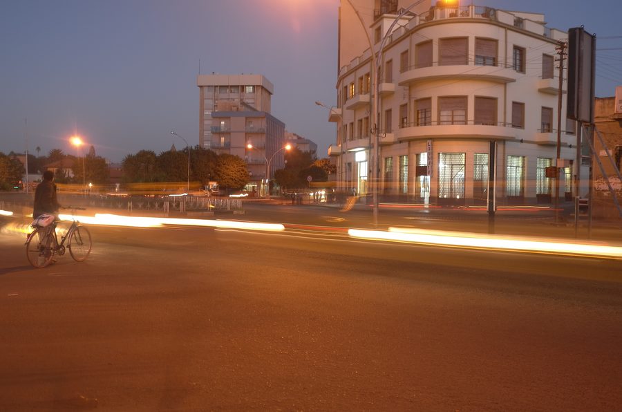 Night view of Asmara with illuminated colonial-era buildings and city lights.
