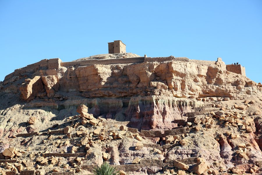 Blick auf den Ksar von Aït Ben Haddou auf einem Hügel in einer trockenen Landschaft in Marokko.