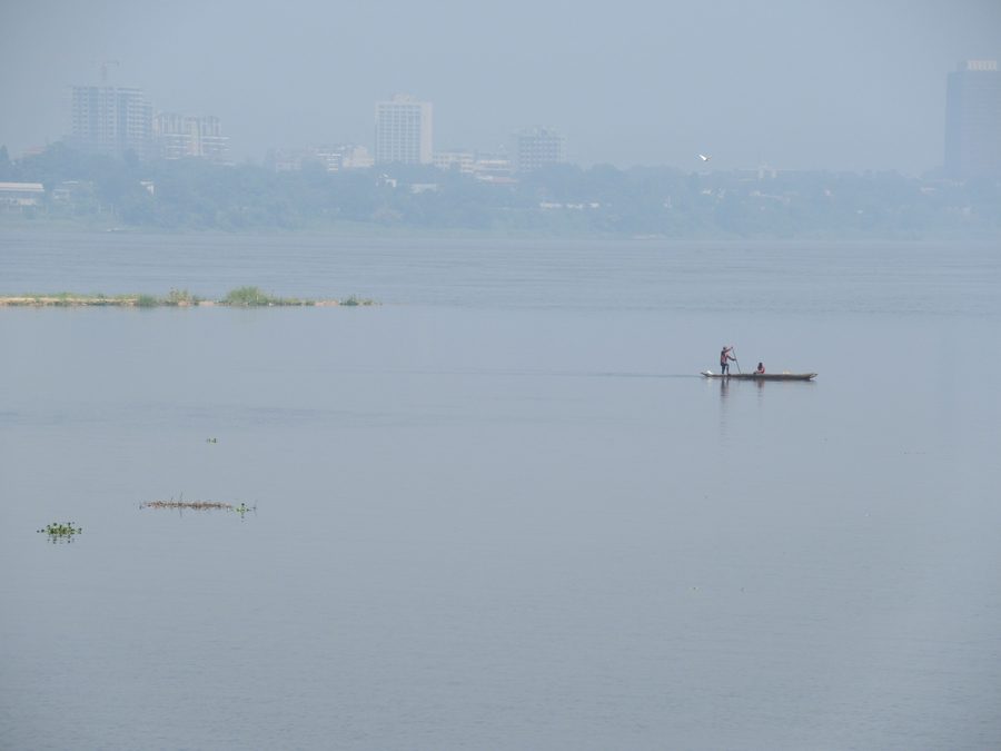 Canoe on the Congo River near Brazzaville, with Kinshasa visible across the water.