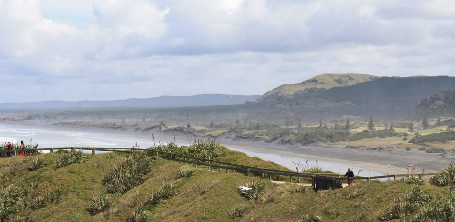 Muriwai Beach mit schwarzem Sand und felsiger Küste in Neuseeland